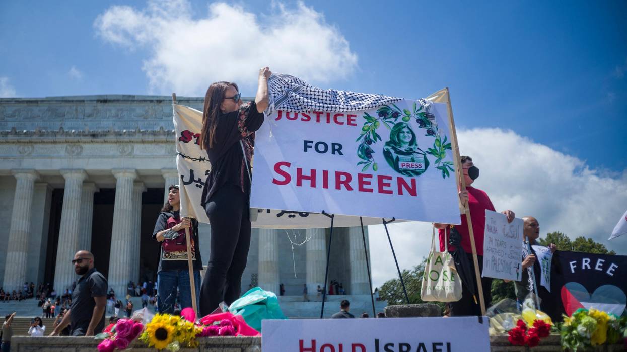 A woman drapes a keffiyeh on a banner calling for justice for slain Palestinian American journalist Shireen Abu Akleh