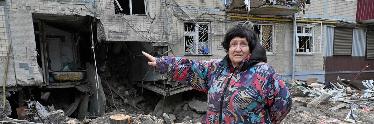 A woman gestures toward damage done by bombing in Kharkiv