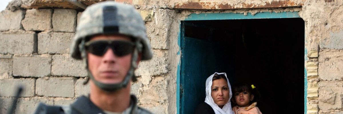 A woman holding her child looks at U.S. soldier in Iraq in 2008