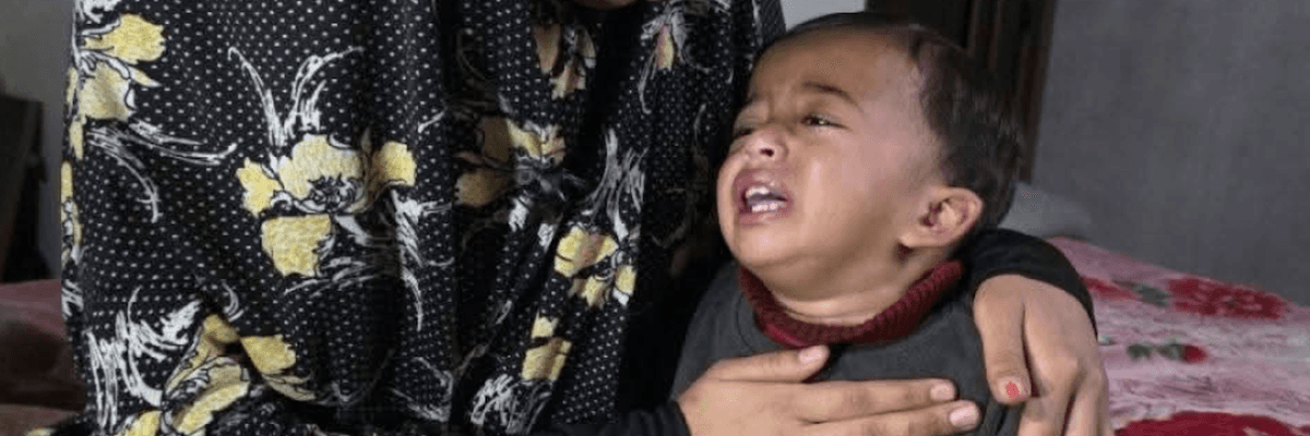 A woman holds 1-year-old Karim, who is crying