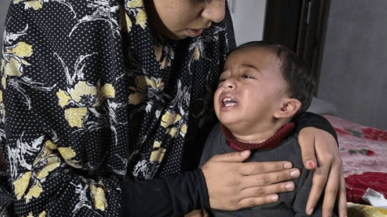 A woman holds 1-year-old Karim, who is crying