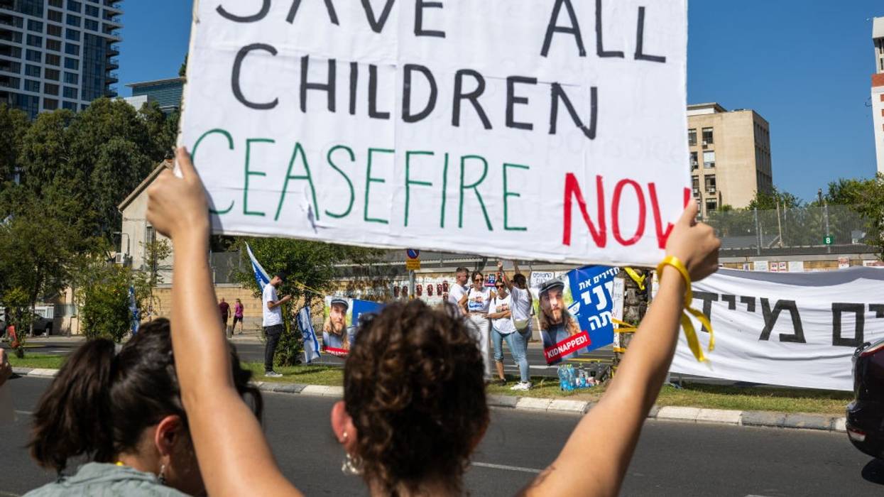 A woman holds a "Save all children, ceasefire now" sign