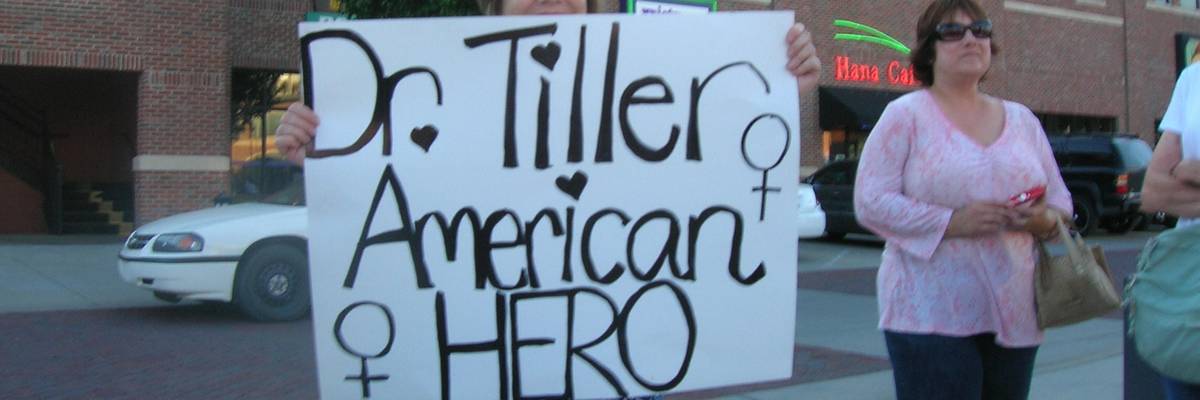 A woman holds a sign reading, "Dr. Tiller American Hero."