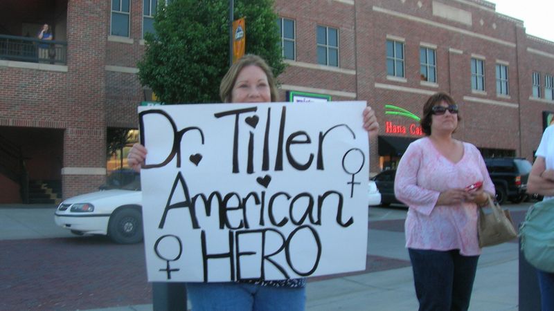 A woman holds a sign reading, "Dr. Tiller American Hero."