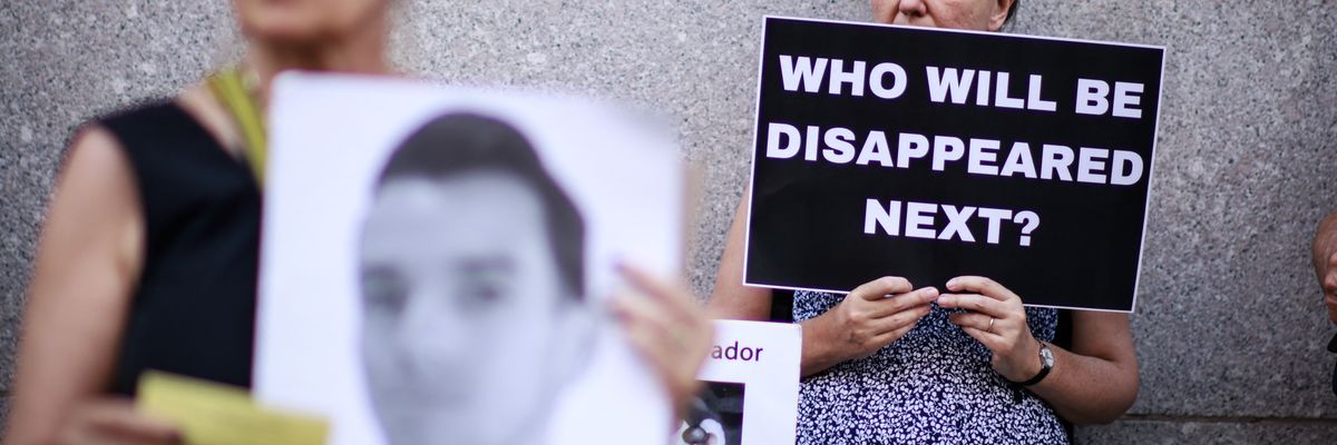 A woman holds a sign reading, "Who Will Be Disappeared Next"