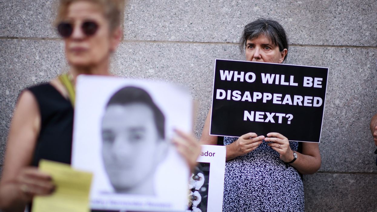 A woman holds a sign reading, "Who Will Be Disappeared Next"