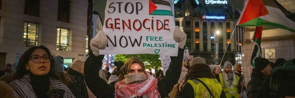 A woman holds a sign saying "Stop Genocide Now, Free Palestine" at an Oslo protest.