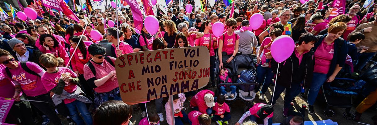 A woman holds a sign that says, "You explain to my son that I am not his mother" as children wear shirts that say, "It is love that creates a family" during a pro-equality demonstration in Milan, Italy on March 18, 2023.