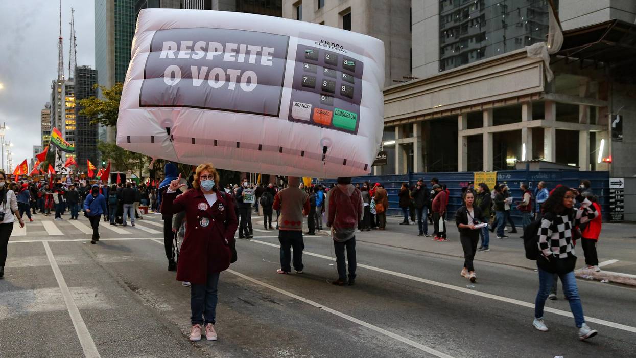 A woman holds sign reading "Respect the Vote in Brazil