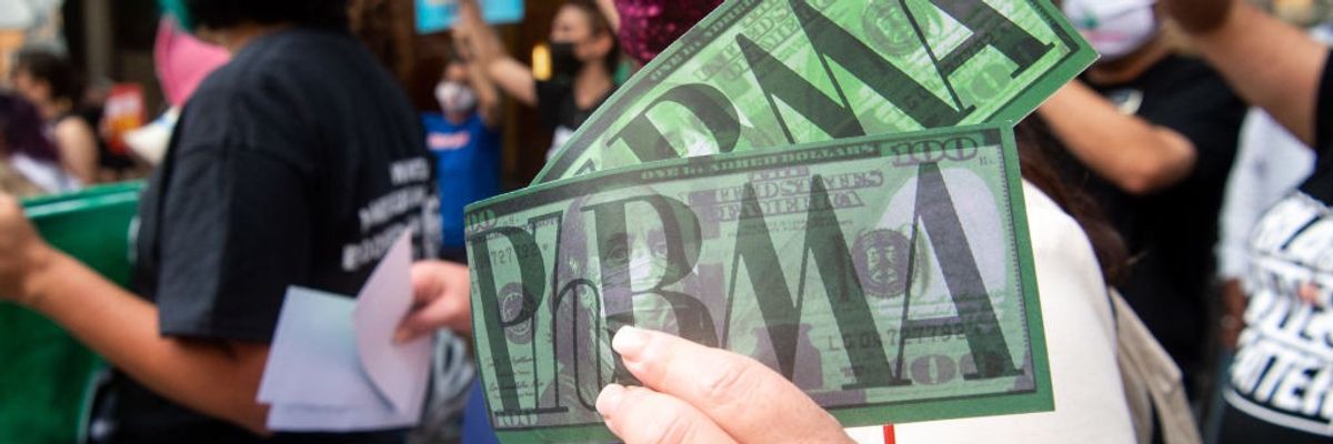 A woman holds two dollar bills saying, "PhRMA."