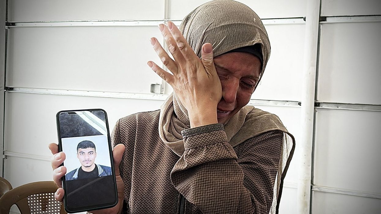 A woman holds up a mobile phone showing a picture of a relative inside Nasser Hospital