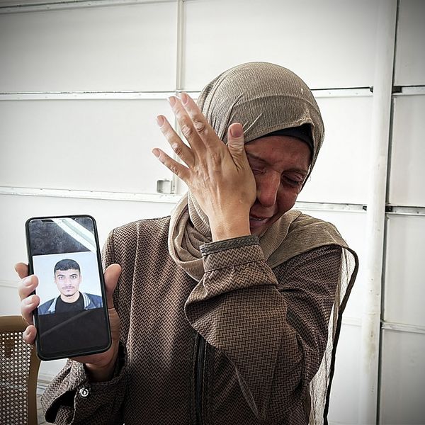 A woman holds up a mobile phone showing a picture of a relative inside Nasser Hospital