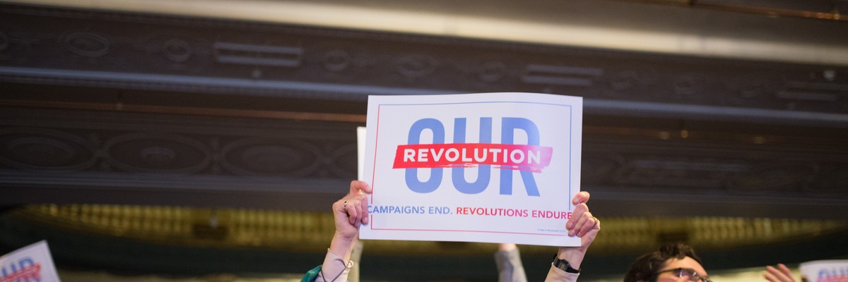 A woman holds up an Our Revolution sign.