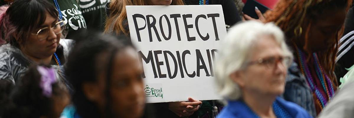 A woman in a crowd holds a sign reading, "Protect Medicaid."