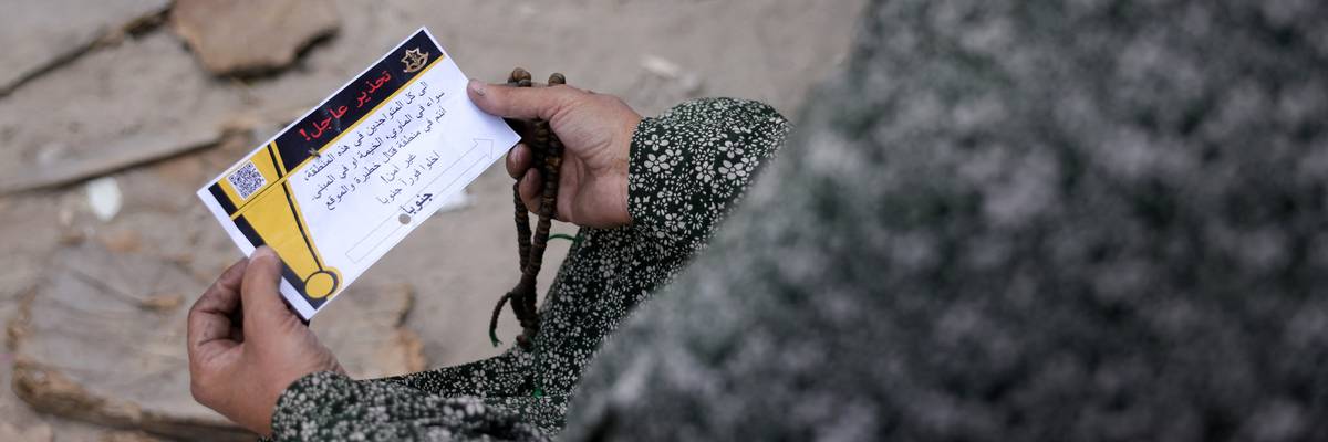 A woman in Gaza holds a leaflet from the Israeli military.