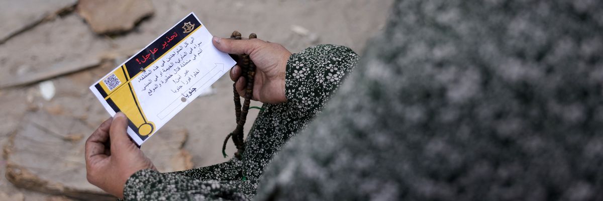 A woman in Gaza holds a leaflet from the Israeli military.