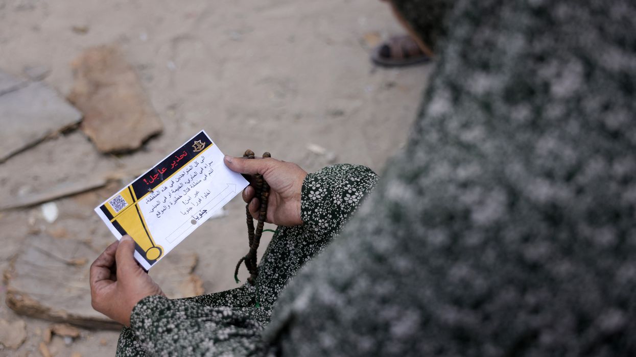 A woman in Gaza holds a leaflet from the Israeli military.