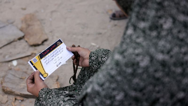 A woman in Gaza holds a leaflet from the Israeli military.