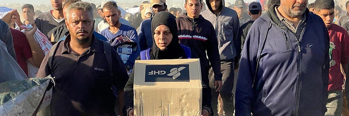 A woman in Gaza with a GHF box in a crowd.