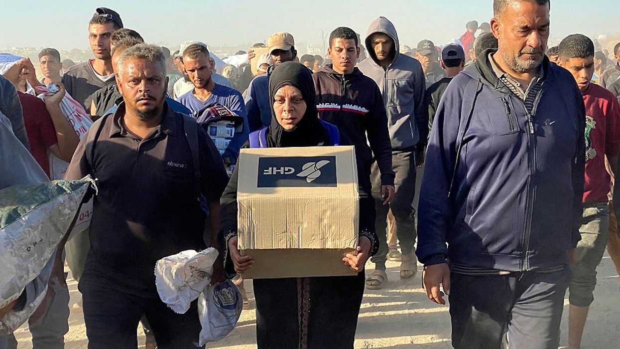 A woman in Gaza with a GHF box in a crowd.