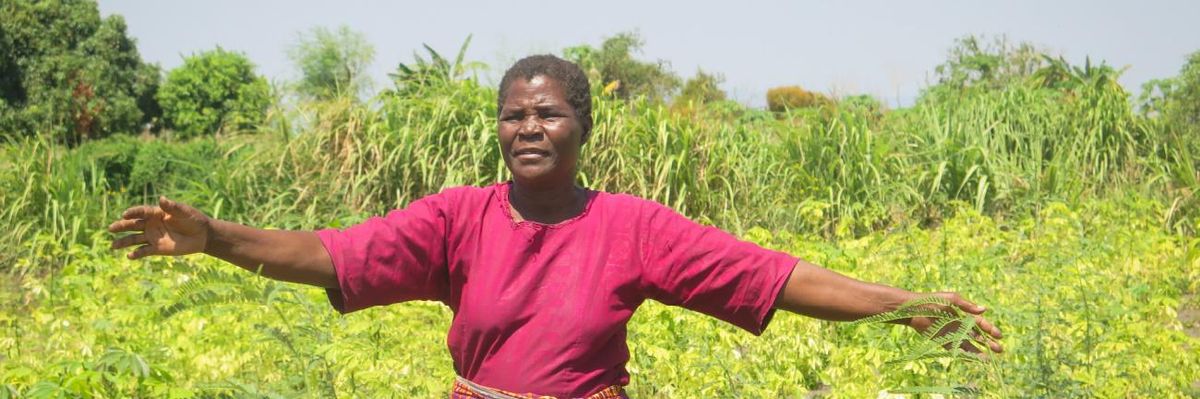 A woman in Malawi gestures to crops