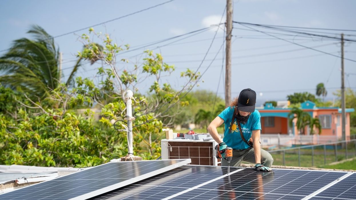 A woman installs a rooftop solar panel in Puerto Rico