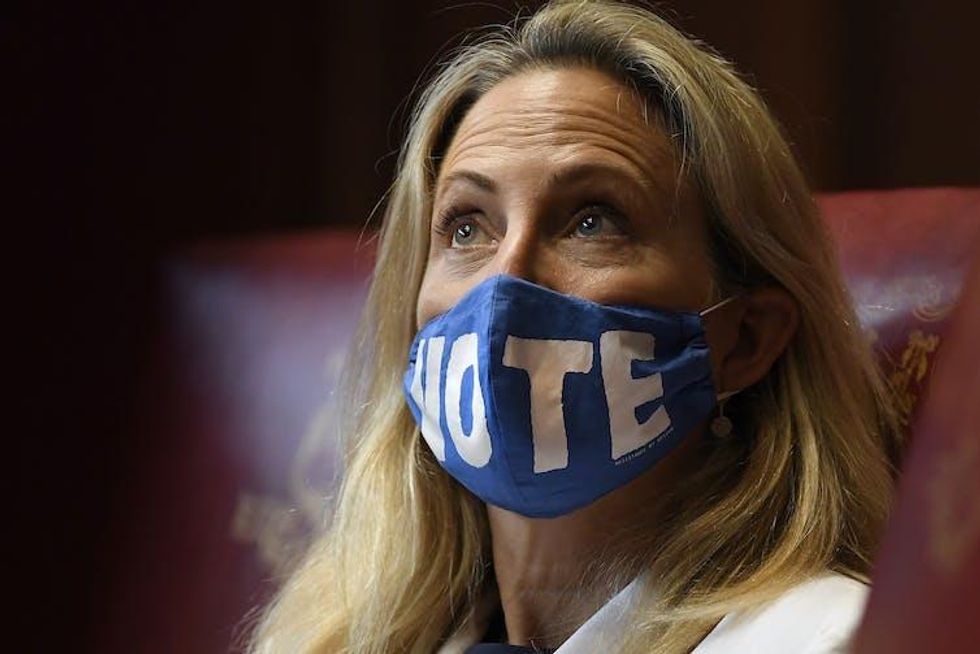 A woman looking up wearing a blue mask with the word 'VOTE' on it.