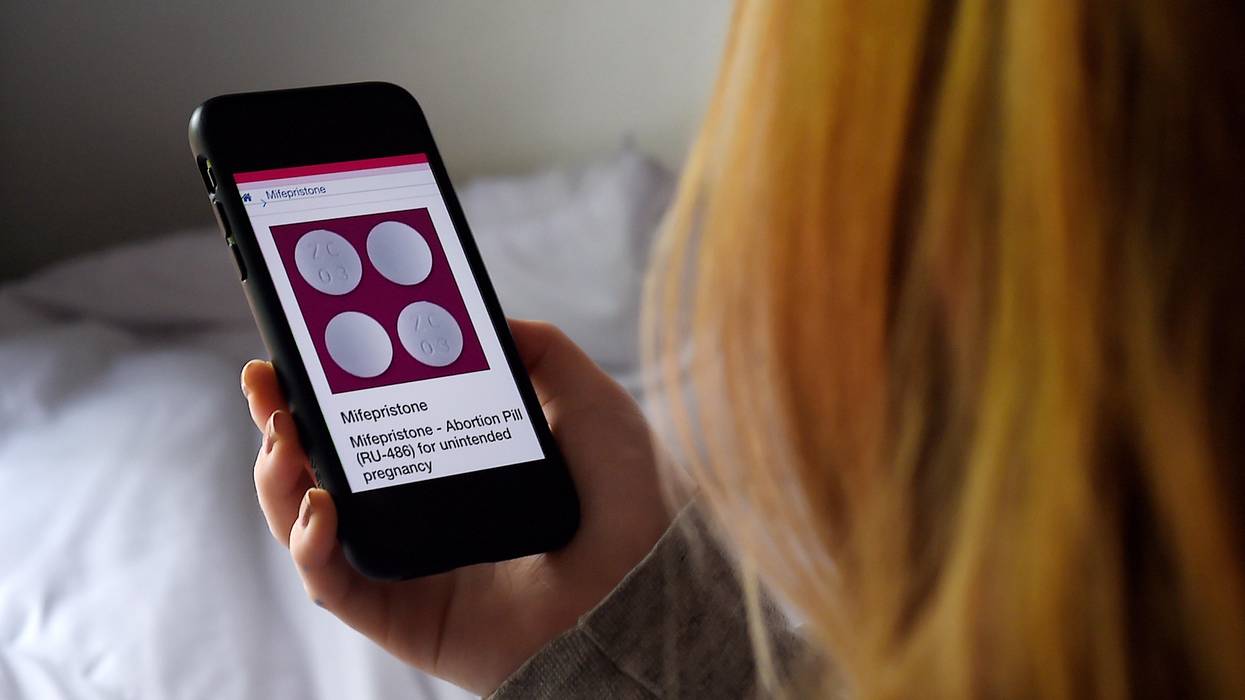 A woman looks at a pill used for medication abortion