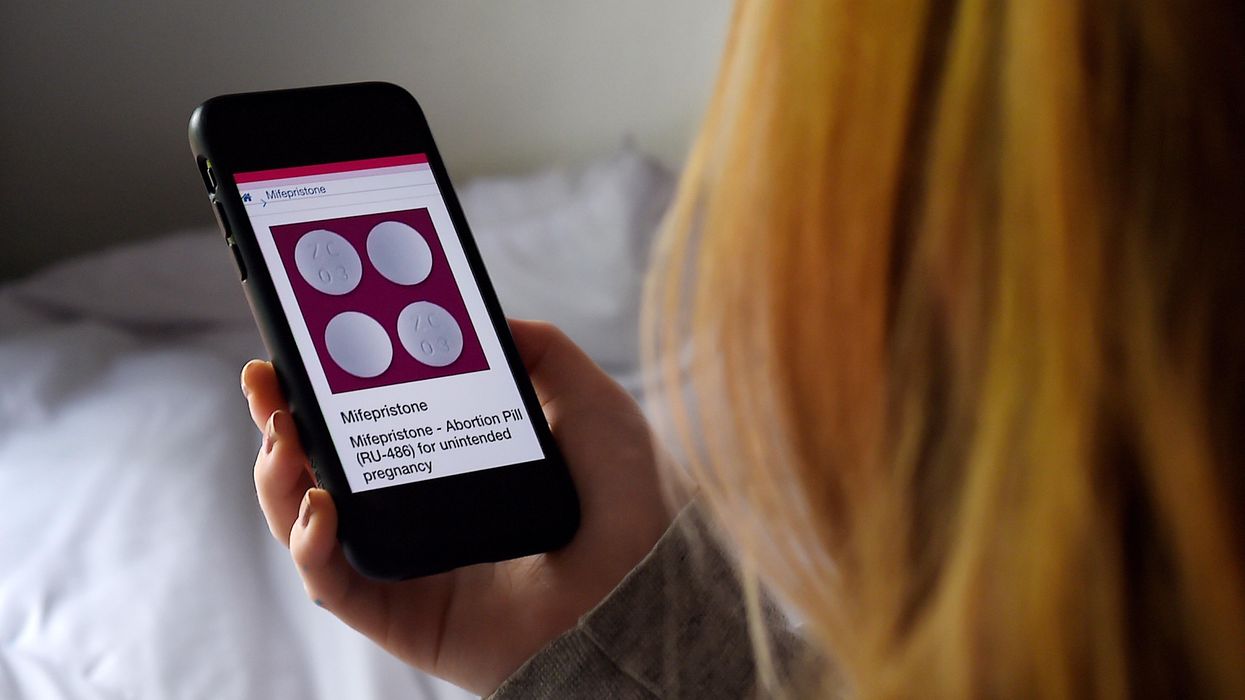 A woman looks at a pill used for medication abortion
