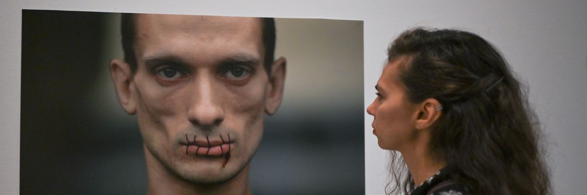 A woman looks at photo of Pyotr Pavlensky, who sewed his mouth to express his solidarity with women of Pussy Riot