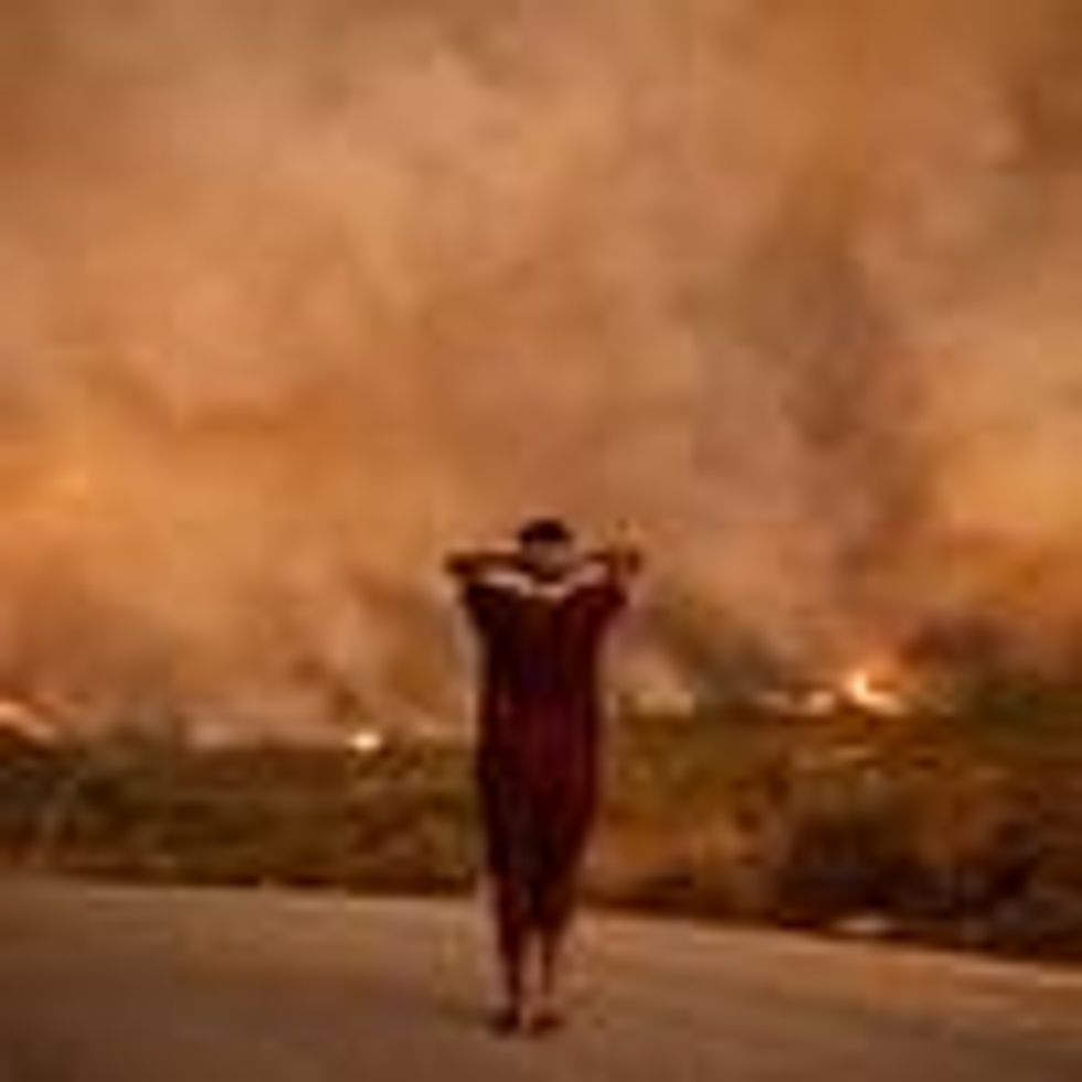 A woman looks at wildfires tearing through a forest in the region of Chefchaouen in northern Morocco on August 15, 2021.