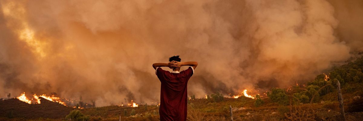 A woman looks at wildfires tearing through a forest