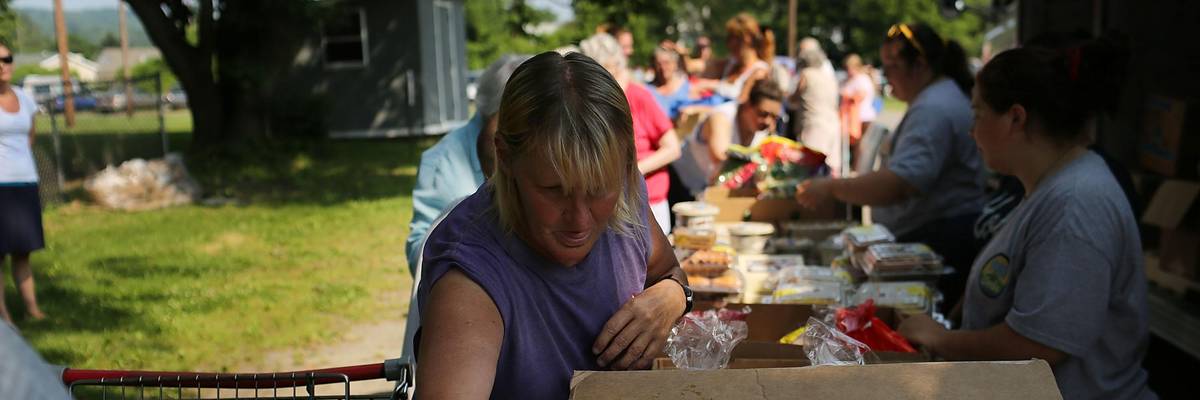 A woman looks through a box at a food bank.