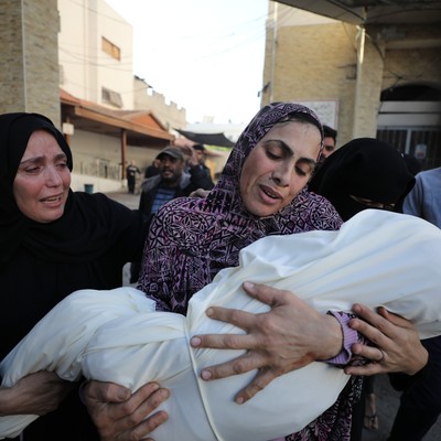 A woman mourns as she carries the body of a child killed in Israeli attacks