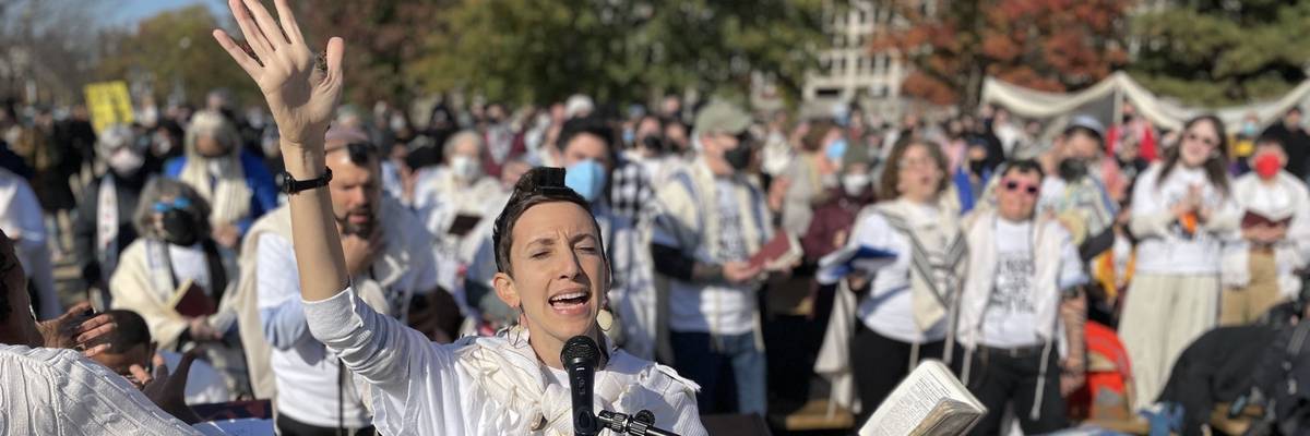A woman prays into a microphone.
