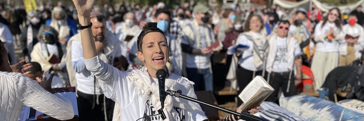 A woman prays into a microphone.