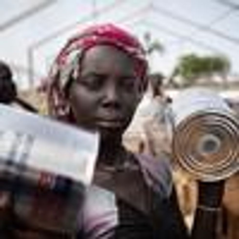 A woman receives cans of oil at a food distribution in South Sudan