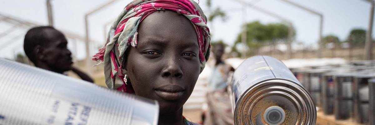 A woman receives cans of oil at a food distribution in South Sudan