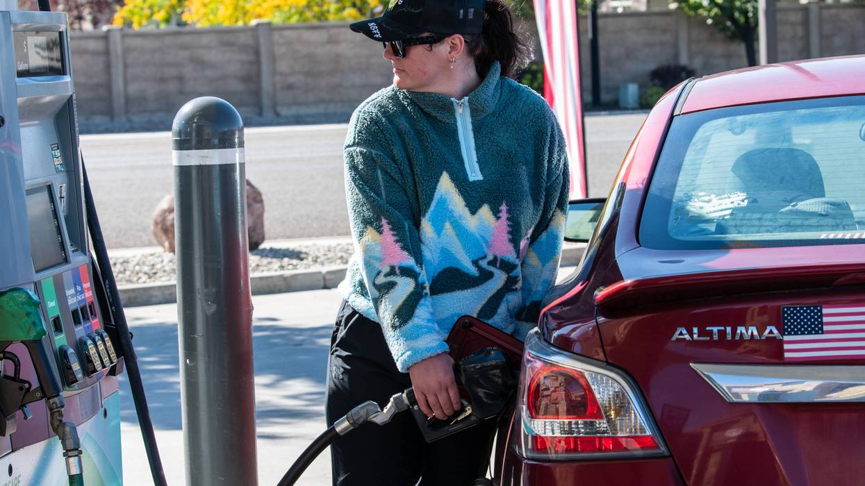 A woman refuels a vehicle at a gas station