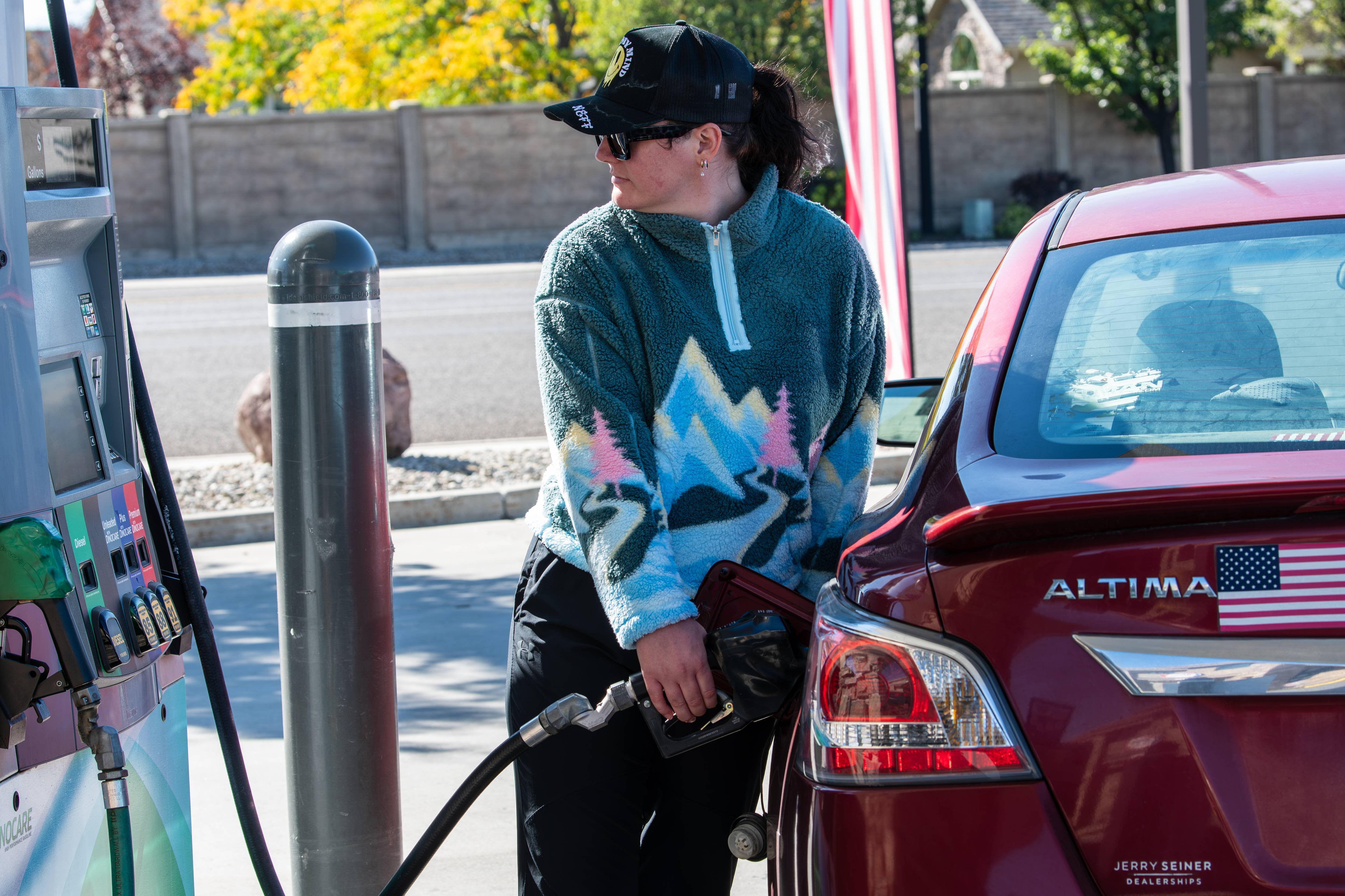 A woman refuels a vehicle at a gas station