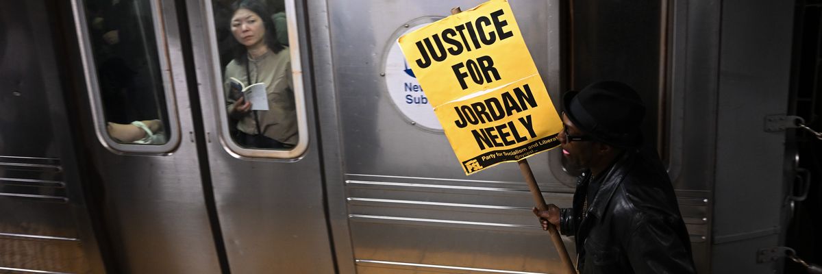 A woman riding the subway looks at a protestor carrying a "Justice for Jordan Neely" sign at the Broadway-Lafayette station on May 08, 2023 in New York City.