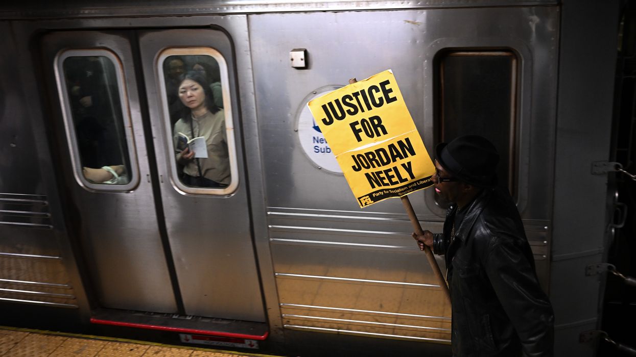 A woman riding the subway looks at a protestor carrying a "Justice for Jordan Neely" sign at the Broadway-Lafayette station on May 08, 2023 in New York City.