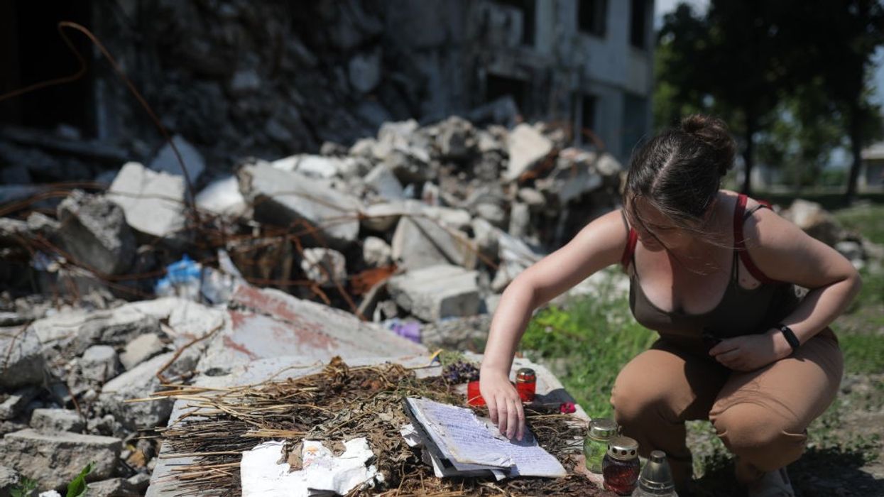 A woman searches through rubble in Ukraine.