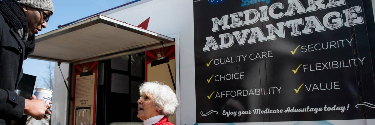 A woman speaks with pedestrians about the supposed benefits of Medicare Advantage