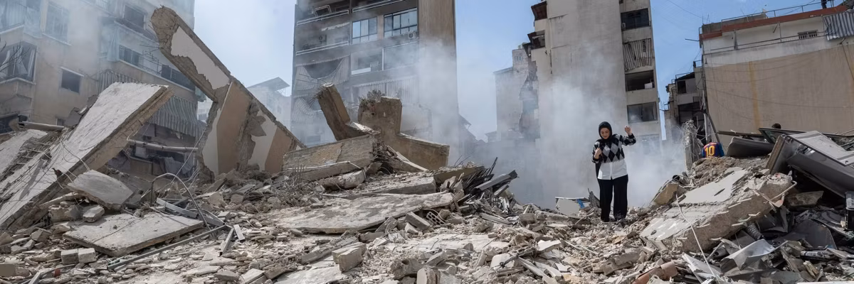 A woman stands amid the rubble of a bombed apartment tower in Beirut