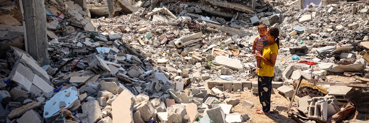 A woman stands holding a child in Gaza