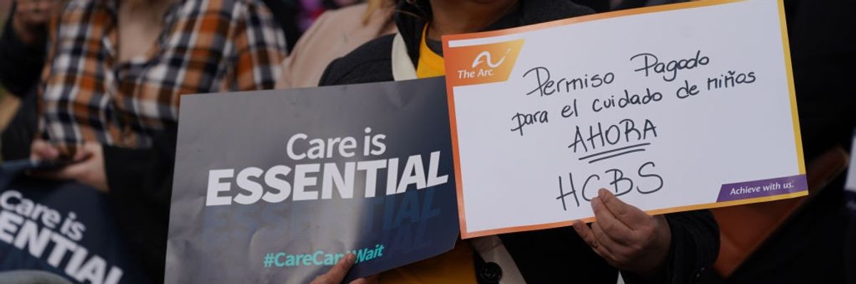 A woman stands with signs advocating care funding.