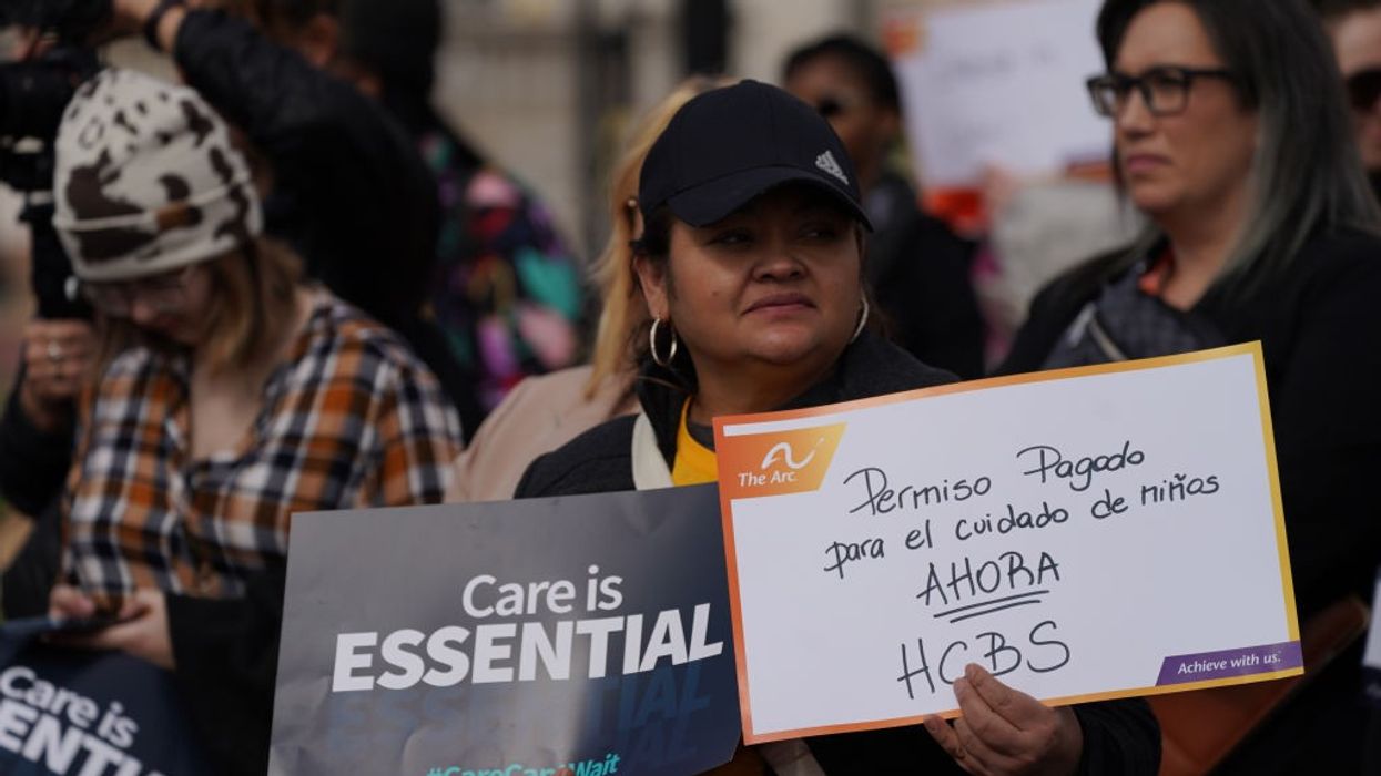 A woman stands with signs advocating care funding.
