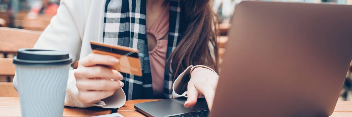 A woman types credit card information on a laptop.