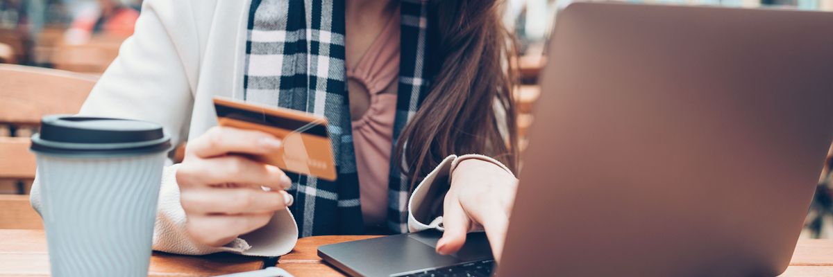 A woman types credit card information on a laptop.